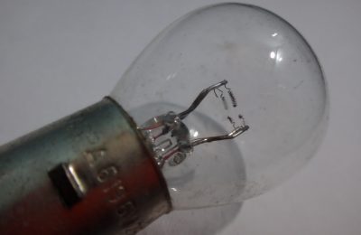 A single automotive filament bulb held against a plain background
