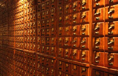A wall of small wooden index drawers with brass label holders